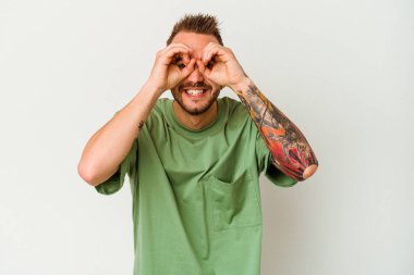 Beyaz arka planda izole edilmiş genç dövmeli beyaz bir adam gözlerde sorun olmadığını gösteriyor.