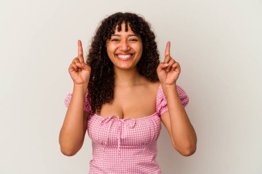 Beyaz arka planda izole edilmiş genç melez kadın iki parmağı da boş bir alan gösteriyor..