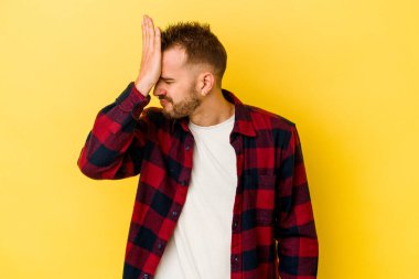 Sarı arka planda izole edilmiş genç, beyaz bir adam bir şeyi unutuyor, alnına avuç içi ve kapalı gözlerle vuruyor..