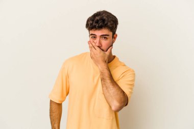 Beyaz arka planda izole edilmiş genç beyaz bir adam ağzı kapalı ve elleri endişeli görünüyor..