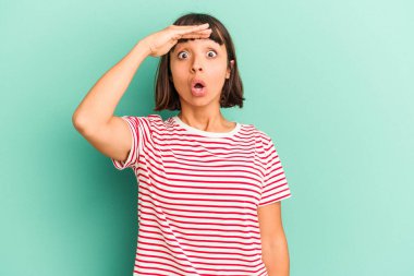 Genç melez kadın maviden izole edilmiş, uzaklara bakıyor ve elini alnına koyuyor..