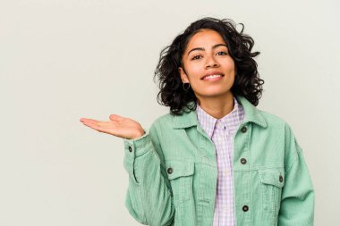 Beyaz arka planda izole edilmiş genç kıvırcık Latin kadın bir avuç içinde fotokopi alanı gösteriyor ve belinde başka bir el tutuyor..