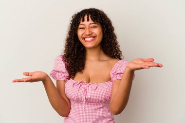 Beyaz arka planda soyutlanmış genç melez kadın kollarıyla ölçeği yapıyor, mutlu ve kendinden emin hissediyor..