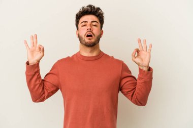 Beyaz arka planda izole edilmiş genç beyaz adam yoğun bir günün ardından rahatlıyor. Yoga yapıyor..