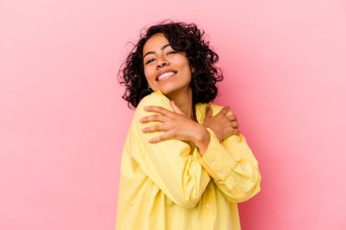 Genç kıvırcık Latin kadın pembe arka planda izole edilmiş, güler yüzlü ve mutlu..