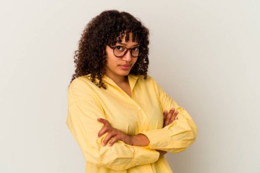 Beyaz arka planda soyutlanmış, hoşnutsuzca kaşlarını çatan, kollarını kavuşturan genç melez bir kadın..