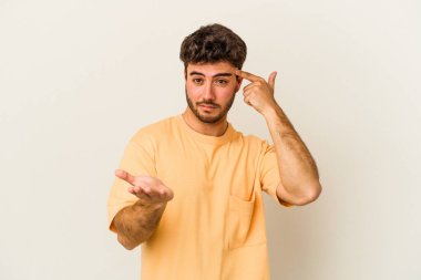 Beyaz arka planda izole edilmiş genç beyaz bir adam elinde bir ürün tutuyor ve.