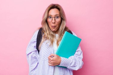 Genç Avustralyalı bir öğrenci pembe arka planda izole edilmiş omuzlarını silkmiş ve gözleri açık kalmış..