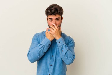 Beyaz arka planda izole edilmiş genç beyaz bir adam ağzı kapalı ve elleri endişeli görünüyor..