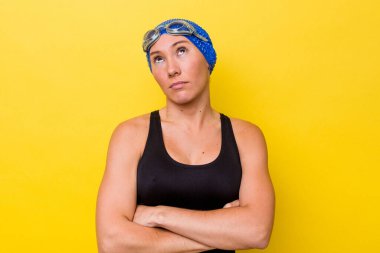 Genç Avustralyalı yüzücü kadın sarı arka planda izole edilmiş. Tekrarlanan bir görevden yorulmuş..