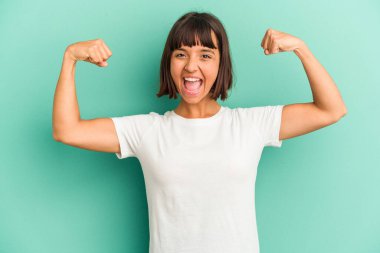 Mavi üzerine izole edilmiş genç bir ırk kadını güçlü bir jest yapıyor, kollarıyla, kadınsı gücün sembolü.