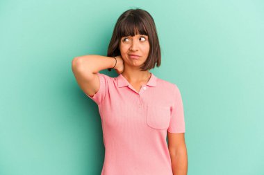 Genç melez kadın mavi üzerine izole edilmiş kafasının arkasına dokunuyor, düşünüyor ve bir seçim yapıyor..