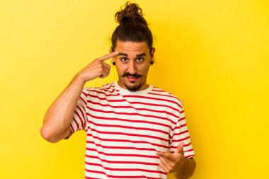 Sarı arka planda uzun saçlı beyaz bir adam işaret parmağıyla hayal kırıklığı gösteriyor..