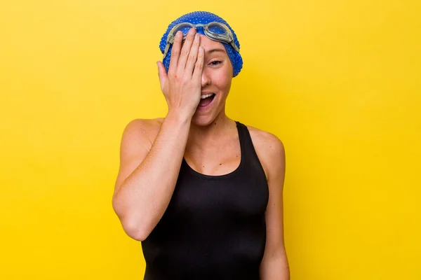 年轻的澳大利亚游泳女子 在黄色背景下被隔离 有乐趣地用手掌捂住半个脸 — 图库照片