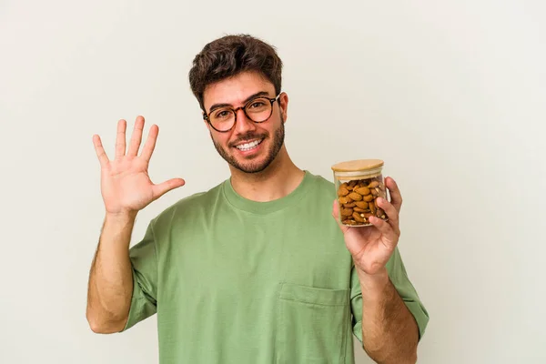 Joven Hombre Caucásico Sosteniendo Frasco Almendras Aislado Sobre Fondo Blanco — Foto de Stock