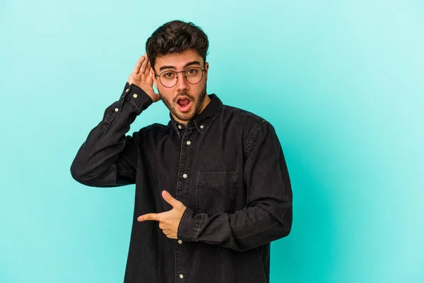 Joven Hombre Caucásico Aislado Sobre Fondo Azul Tratando Escuchar Chisme —  Fotos de Stock