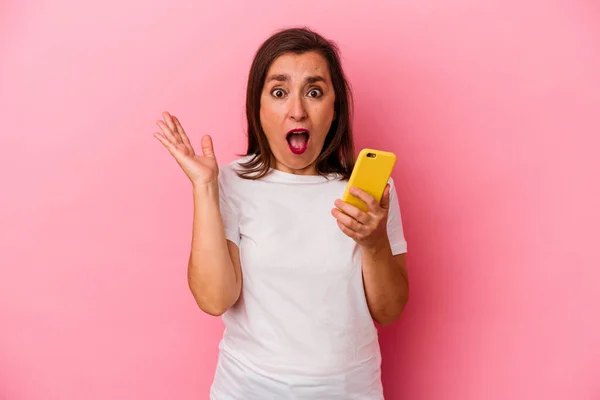 Medelåldern Kaukasiska Kvinna Som Håller Mobiltelefon Isolerad Rosa Bakgrund Förvånad — Stockfoto