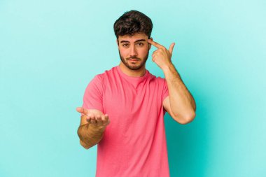 Kafkasyalı genç adam mavi arka planda izole edilmiş ve elinde bir ürün tutuyor..