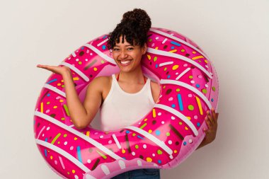 Beyaz arka planda izole edilmiş şişme bir donut tutan genç melez kadın bir avuç içinde fotokopi alanı ve belinde başka bir el tutuyor..