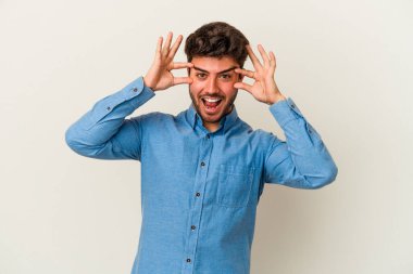 Beyaz arka planda izole edilmiş genç beyaz bir adam bir başarı fırsatı bulmak için gözlerini açık tutuyor..