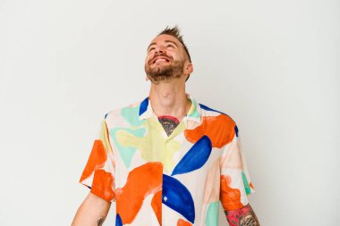 Beyaz arka planda izole edilmiş genç, dövmeli beyaz bir adam. Rahatlamış ve mutlu bir gülüş, boynunda dişler olan..