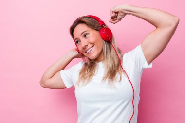 Pembe arka planda müzik dinleyen genç Avustralyalı kadın zaferden sonra yumruğunu kaldırdı, kazanan konsept.