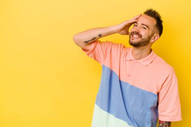 Sarı arka planda izole edilmiş genç dövmeli beyaz adam gülüyor, kaygısız, doğal duygu..