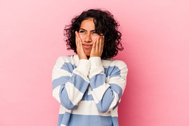 Genç kıvırcık Latin kadın pembe arka planda izole edilmiş sızlanıyor ve ağlıyordu..