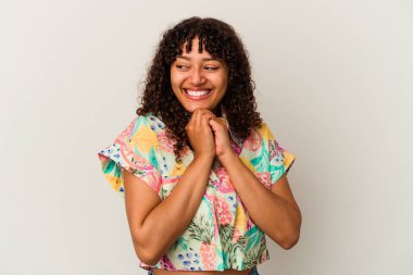 Beyaz arka planda izole edilmiş genç melez kadın ellerini çenesinin altında tutuyor ve mutlu bir şekilde yan tarafa bakıyor..