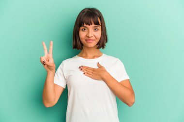 Genç melez kadın mavi üzerine izole edilmiş yemin ediyor, elini göğsüne koyuyor..