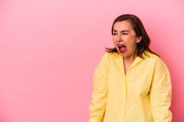 Pembe arka planda izole edilmiş orta yaşlı beyaz kadın çok kızgın, öfkeli, hayal kırıklığına uğramış.