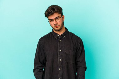 Kafkasyalı genç adam mavi arka planda izole edilmiş üzgün, ciddi yüzlü, mutsuz ve hoşnutsuz..