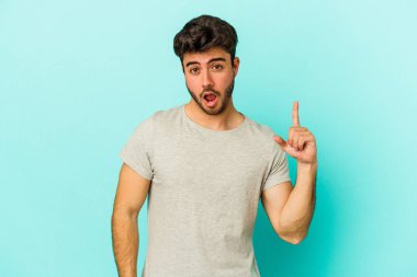 Kafkasyalı genç bir adam mavi arka planda izole edilmiş. Bir fikri, ilham verici bir fikri var..