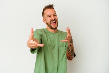 Beyaz arka planda izole edilmiş genç dövmeli beyaz adam kameraya sarıldığı için kendini güvende hissediyor..