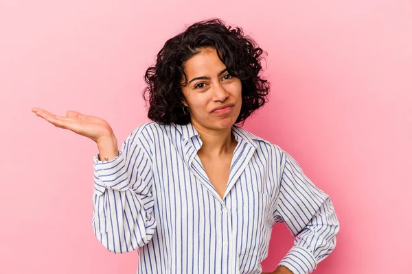 若いですラテン巻き女性隔離上のピンクの背景疑問とShrugging肩で質問ジェスチャー — ストック写真