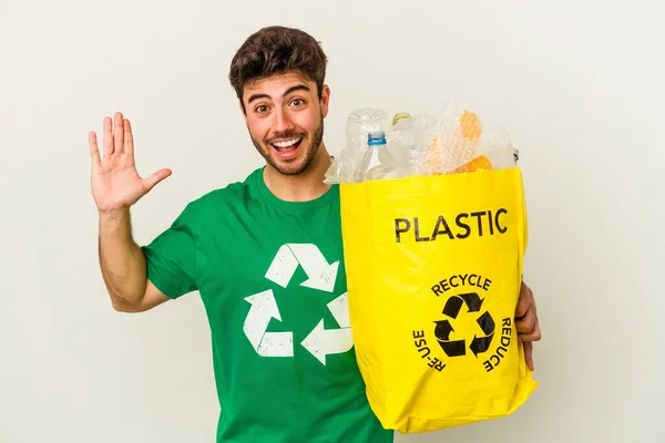 白い背景に隔離された若い白人男性のリサイクルプラスチックは 快適な驚き 興奮し 手を上げる — ストック写真