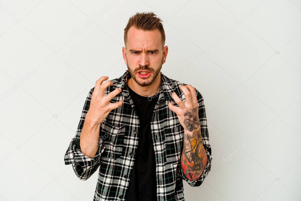 Young tattooed caucasian man isolated on white background upset screaming with tense hands.