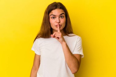 Sarı arka planda izole edilmiş genç beyaz kadın ya sır saklıyor ya da sessizlik istiyor..