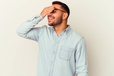 Beyaz arka planda izole olmuş genç beyaz bir adam ellerini başının üstünde tutarak neşeyle gülüyor. Mutluluk kavramı.