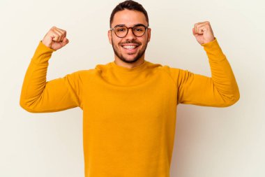 Beyaz arka planda izole edilmiş genç beyaz bir adam güçlü bir hareket gösteriyor, kollarıyla, kadınsı gücün sembolü.