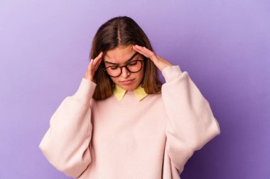 Mor arka planda izole edilmiş genç beyaz kadın şakaklara dokunuyor ve baş ağrısı çekiyor..