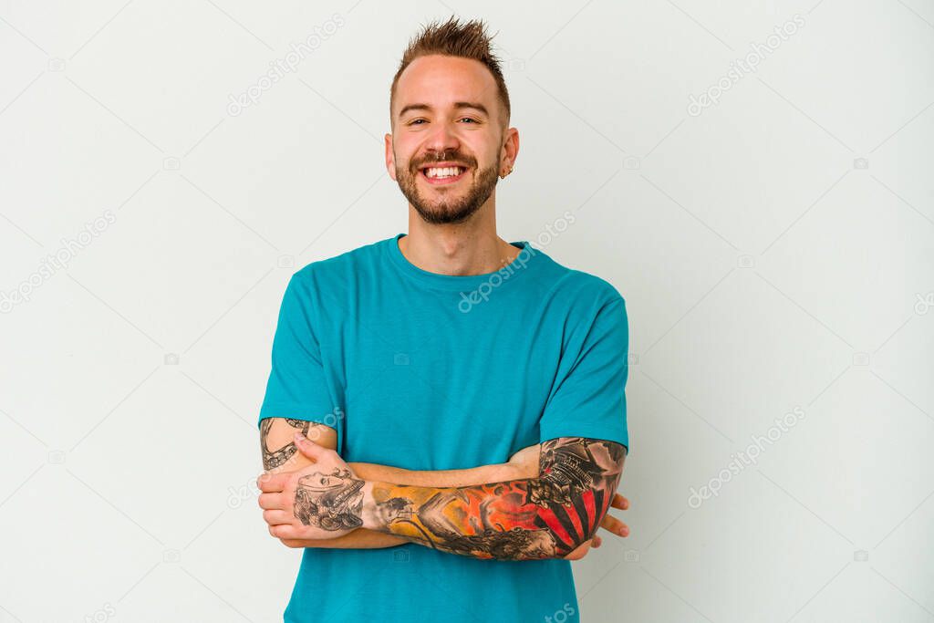 Young tattooed caucasian man isolated on white background who feels confident, crossing arms with determination.