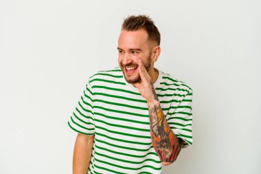 Beyaz arka planda izole edilmiş genç dövmeli beyaz adam heyecanlı bir şekilde öne doğru bağırıyor..