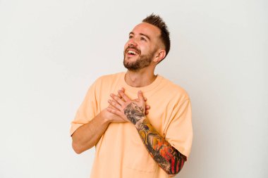 Beyaz arka planda izole edilmiş genç, dövmeli beyaz adam, dost bir ifadeye sahip, avuçlarını göğsüne bastırıyor. Aşk konsepti.