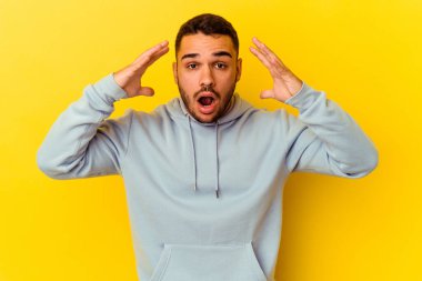 Sarı arka planda izole edilmiş genç beyaz bir adam zaferi ya da başarıyı kutluyor, şaşırıyor ve şok oluyor..