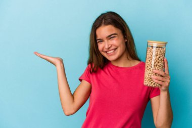 Beyaz arka planda izole edilmiş nohut kavanozu tutan genç beyaz adam bir avuç içinde fotokopi alanı ve belinde başka bir el tutuyor..