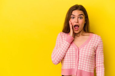 Sarı arka planda izole edilmiş genç beyaz kadın yüksek sesle bağırıyor, gözleri açık ve elleri gergin tutuyor..