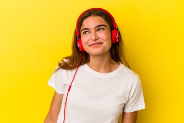 Sarı arka planda müzik dinleyen beyaz bir kadın amaçlarına ve amaçlarına ulaşma hayali kuruyor.