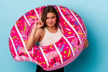 Mavi arka planda izole edilmiş şişme donutu olan beyaz bir kadın parmak ile bir numarayı gösteriyor..