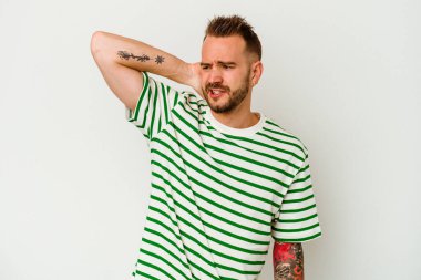 Beyaz arka planda izole edilmiş genç dövmeli beyaz adam yorgun ve uykulu bir şekilde ellerini başının üstünde tutuyor..